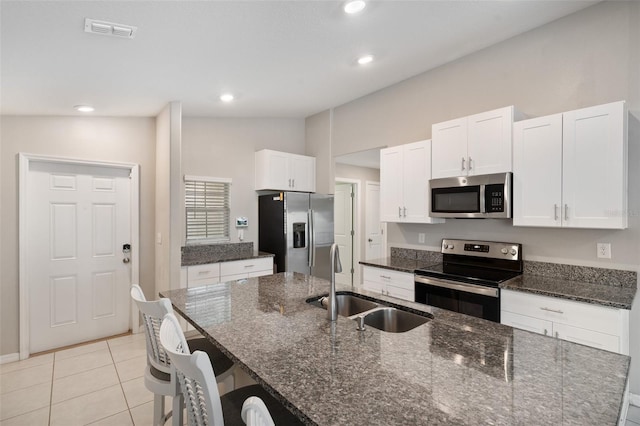 kitchen featuring appliances with stainless steel finishes, sink, dark stone counters, and white cabinets