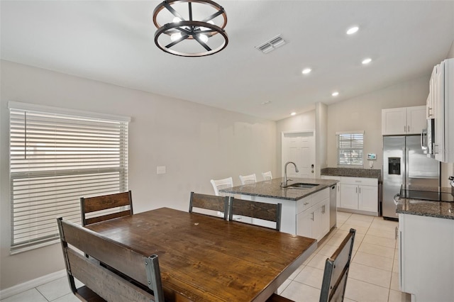 tiled dining area with lofted ceiling and sink