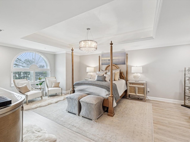 bedroom with crown molding, hardwood / wood-style floors, a tray ceiling, and a chandelier