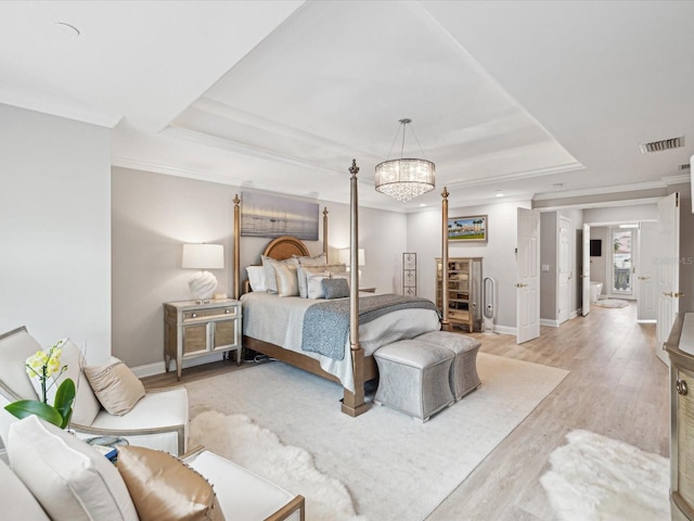 bedroom with ornamental molding, light hardwood / wood-style floors, a raised ceiling, and a chandelier