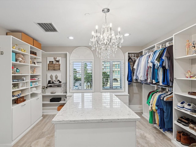 spacious closet with an inviting chandelier and light wood-type flooring