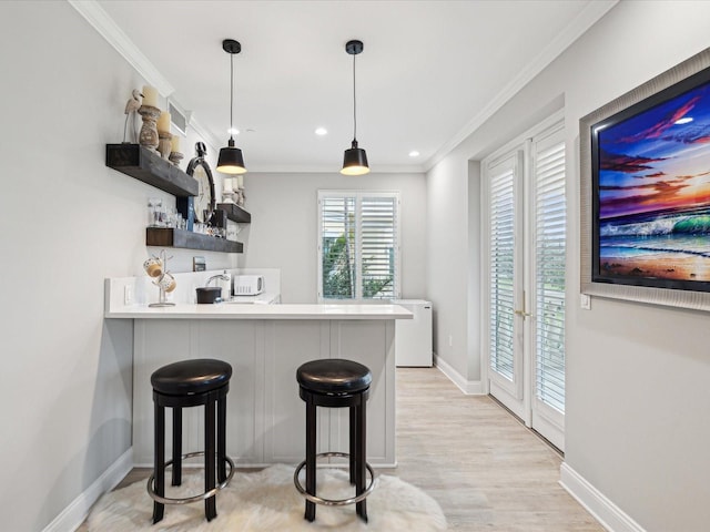 kitchen featuring crown molding, decorative light fixtures, a kitchen breakfast bar, kitchen peninsula, and light hardwood / wood-style floors