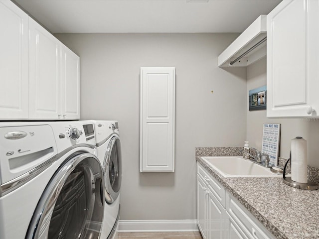 laundry area featuring cabinets, washer and clothes dryer, sink, and light hardwood / wood-style flooring