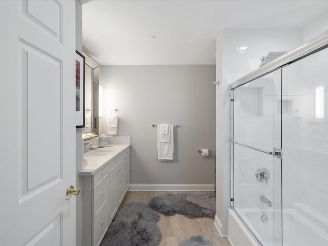 bathroom with vanity, wood-type flooring, and combined bath / shower with glass door