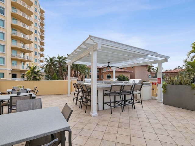 view of patio / terrace featuring area for grilling, a bar, ceiling fan, and a pergola