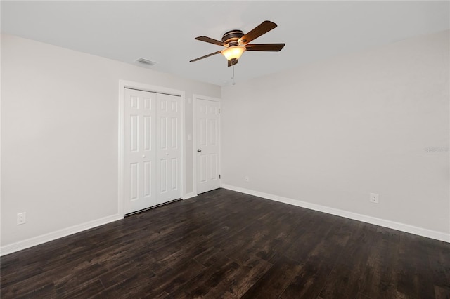 unfurnished bedroom featuring dark wood-type flooring, ceiling fan, and two closets