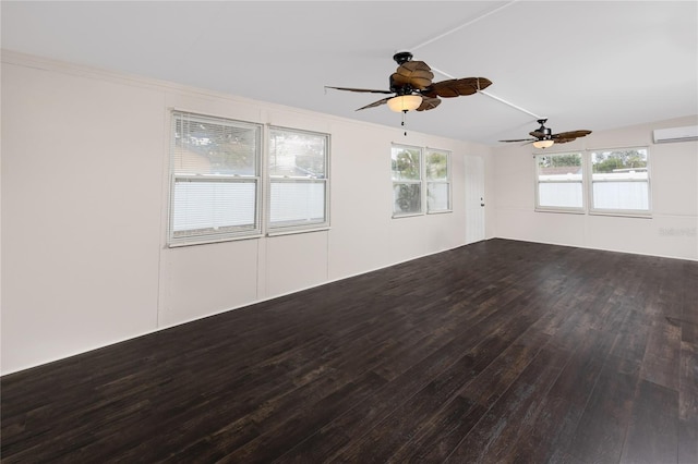 spare room featuring an AC wall unit, hardwood / wood-style floors, ceiling fan, and a healthy amount of sunlight