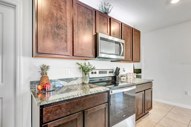 kitchen with light stone countertops, light tile patterned floors, and stainless steel appliances