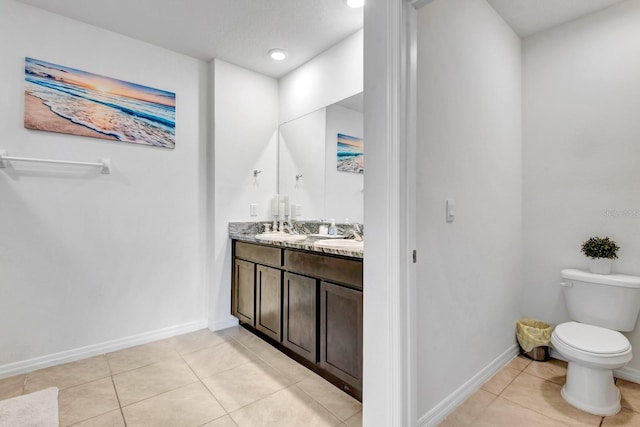 bathroom with toilet, vanity, and tile patterned flooring