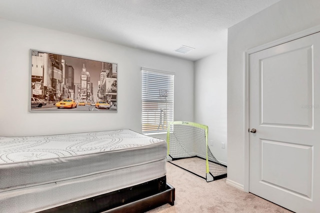 bedroom with light colored carpet and a textured ceiling