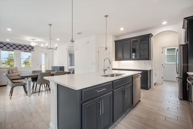 kitchen with sink, decorative light fixtures, an island with sink, stainless steel appliances, and decorative backsplash