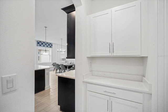 kitchen with white cabinetry, decorative light fixtures, and light hardwood / wood-style floors