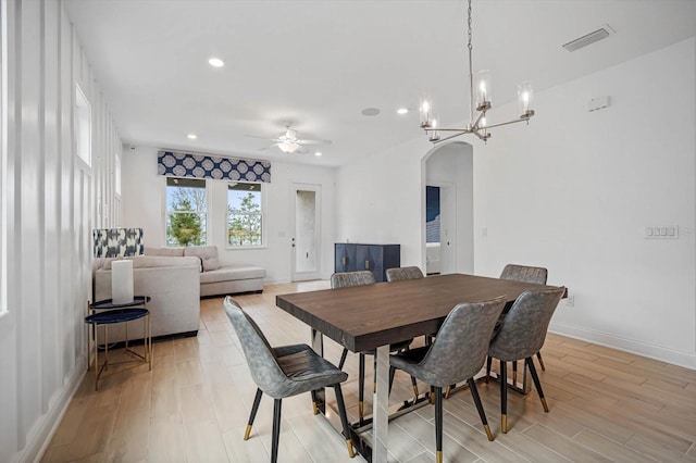 dining space with ceiling fan with notable chandelier and light hardwood / wood-style floors