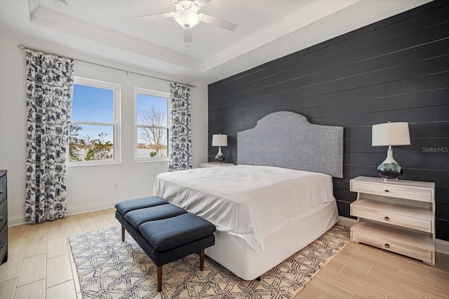 bedroom featuring a tray ceiling, light hardwood / wood-style floors, and ceiling fan