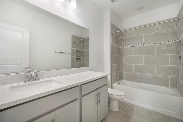 full bathroom featuring tiled shower / bath, vanity, toilet, and tile patterned flooring