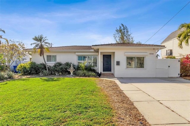 ranch-style home with a gate, stucco siding, a front lawn, concrete driveway, and a tiled roof