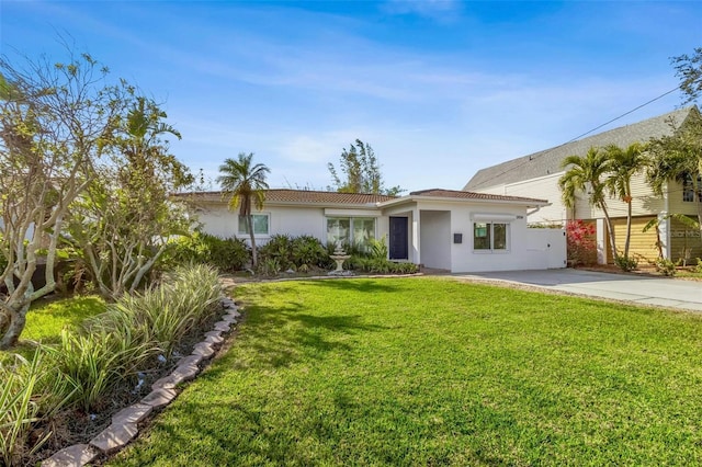 view of front facade with a front yard, driveway, and stucco siding