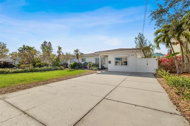 ranch-style home with concrete driveway, a gate, a front lawn, and stucco siding