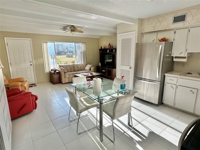 kitchen featuring ceiling fan, light tile patterned flooring, white cabinetry, and stainless steel refrigerator