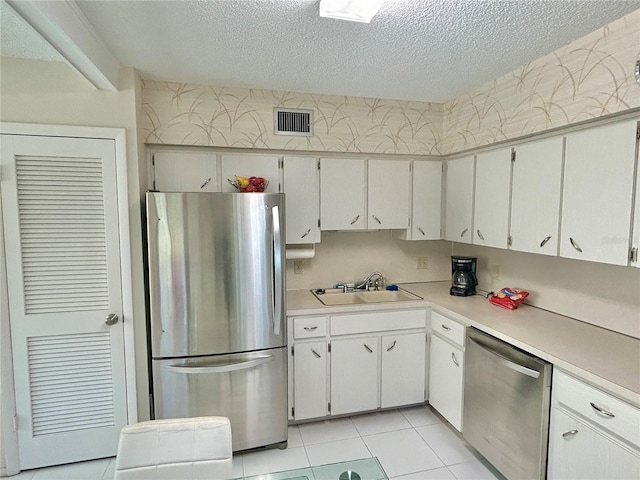 kitchen with light tile patterned flooring, stainless steel appliances, white cabinets, and sink