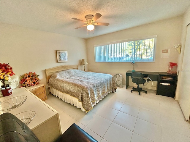 bedroom featuring ceiling fan, light tile patterned floors, and a textured ceiling