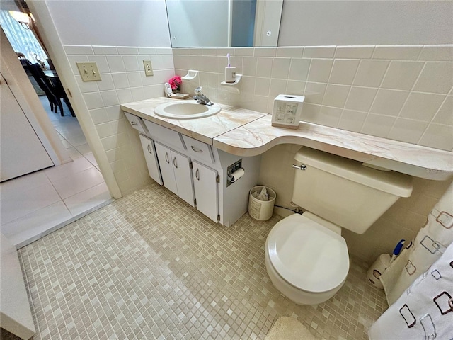 bathroom with tile patterned floors, toilet, vanity, and tile walls