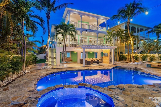 pool at twilight with an in ground hot tub, outdoor lounge area, and a patio area