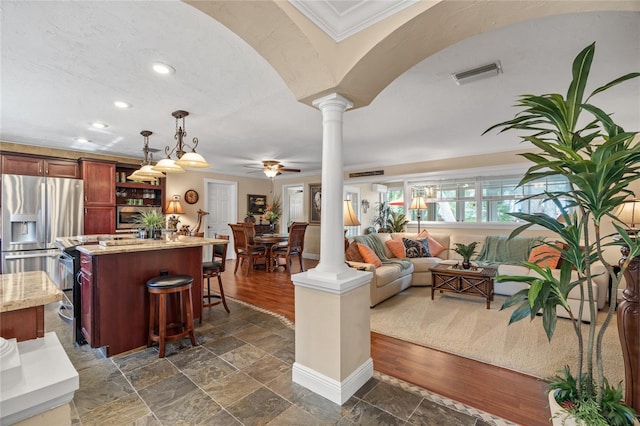 living room with decorative columns, dark hardwood / wood-style flooring, ornamental molding, and ceiling fan