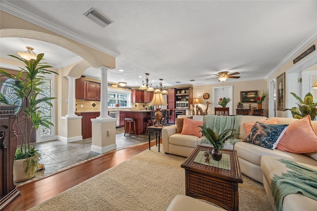 living room featuring ornamental molding, ceiling fan, ornate columns, and wood-type flooring