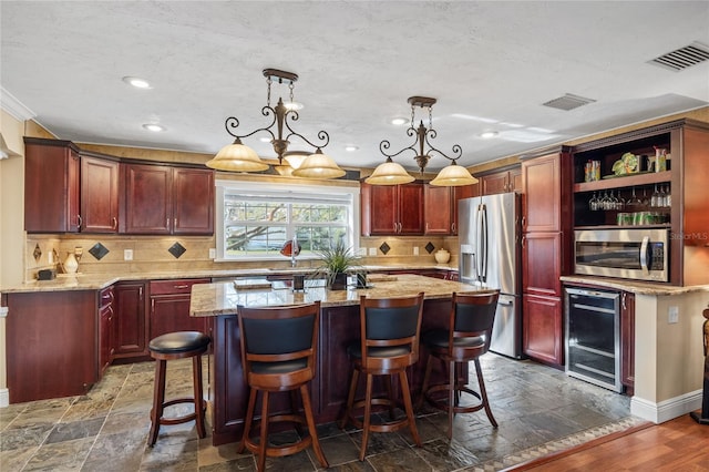 kitchen featuring light stone countertops, hanging light fixtures, a center island, and stainless steel appliances