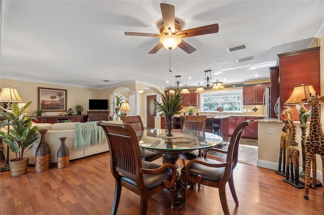 dining room featuring hardwood / wood-style flooring, decorative columns, crown molding, and ceiling fan