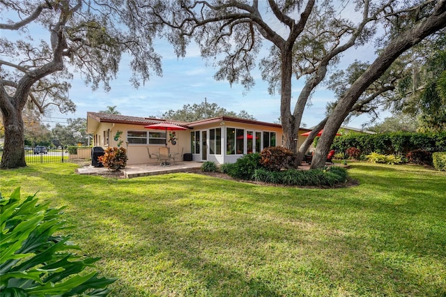 back of property featuring a patio area, a sunroom, and a lawn