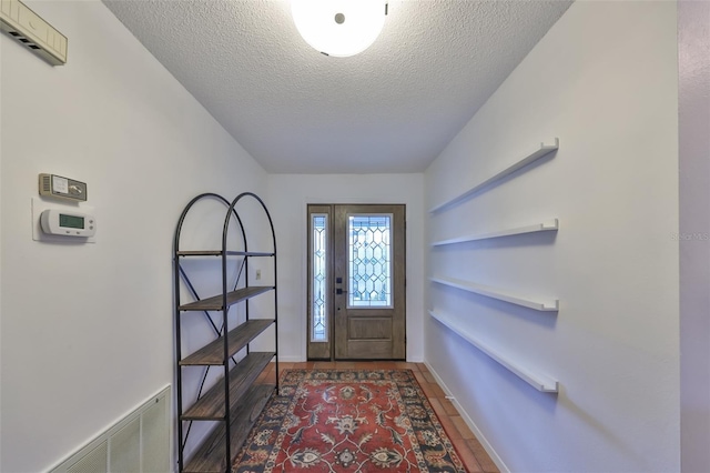 foyer entrance featuring dark tile patterned flooring and a textured ceiling