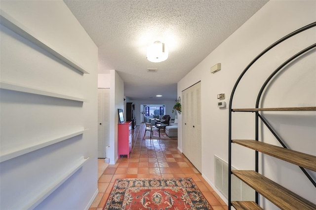 corridor with a textured ceiling and light tile patterned floors