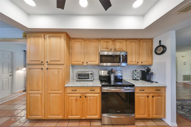 kitchen featuring ceiling fan, backsplash, light stone countertops, stainless steel appliances, and light tile patterned floors