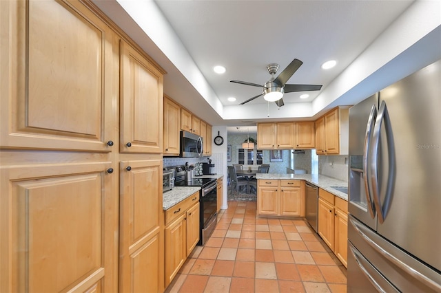 kitchen with light brown cabinets, stainless steel appliances, backsplash, and a raised ceiling