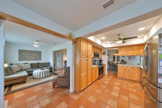 kitchen featuring a tray ceiling, light tile patterned floors, appliances with stainless steel finishes, and tasteful backsplash