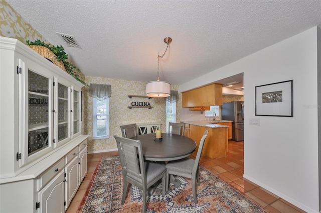 tiled dining space featuring a textured ceiling and sink