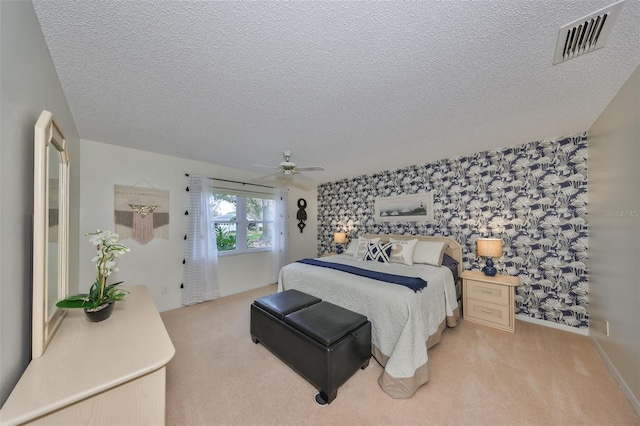 carpeted bedroom featuring ceiling fan and a textured ceiling