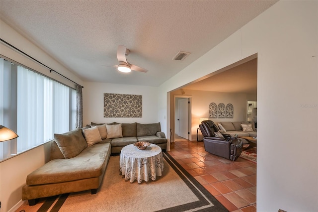 living room with a textured ceiling, ceiling fan, and tile patterned flooring