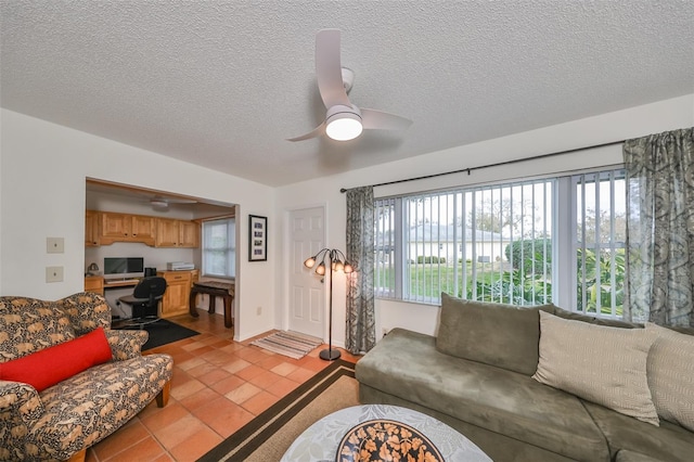 living room with ceiling fan, a wealth of natural light, built in desk, and light tile patterned flooring