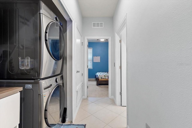 laundry room with stacked washer / drying machine and light tile patterned floors