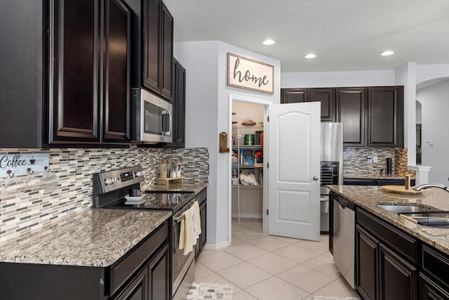 kitchen featuring sink, light tile patterned floors, stainless steel appliances, tasteful backsplash, and light stone countertops