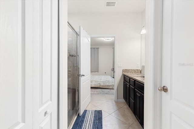 bathroom featuring a shower with door, vanity, and tile patterned floors