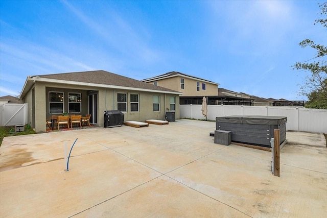 rear view of property with central AC unit, a hot tub, and a patio