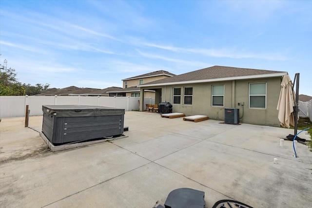 back of property featuring a hot tub, a patio area, and central air condition unit