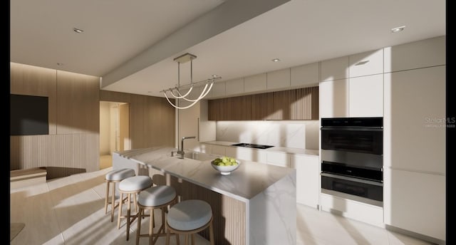 kitchen featuring pendant lighting, white cabinetry, an island with sink, double oven, and black electric cooktop