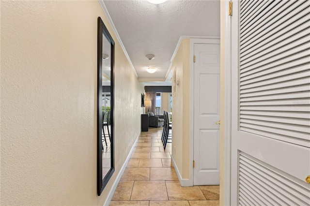 hallway with a textured ceiling, light tile patterned floors, and ornamental molding