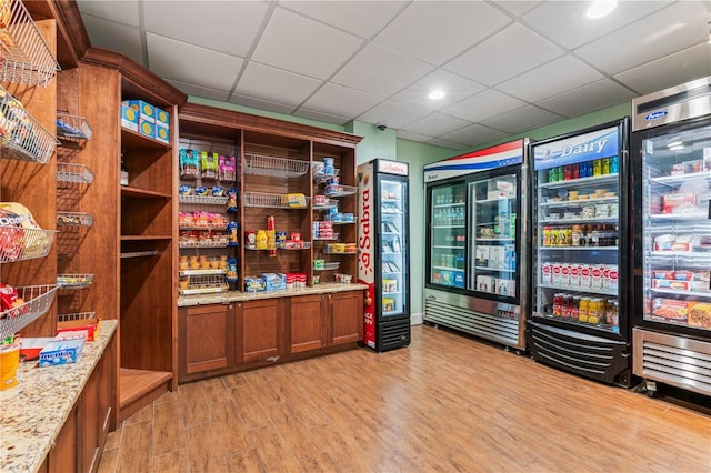 miscellaneous room featuring beverage cooler, a paneled ceiling, and light wood-type flooring