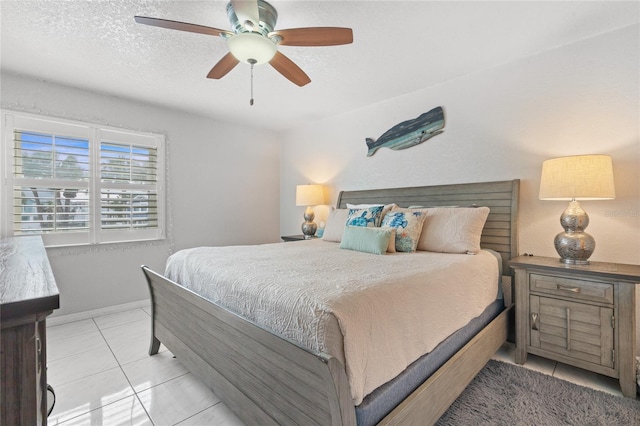 bedroom featuring ceiling fan, light tile patterned floors, and a textured ceiling